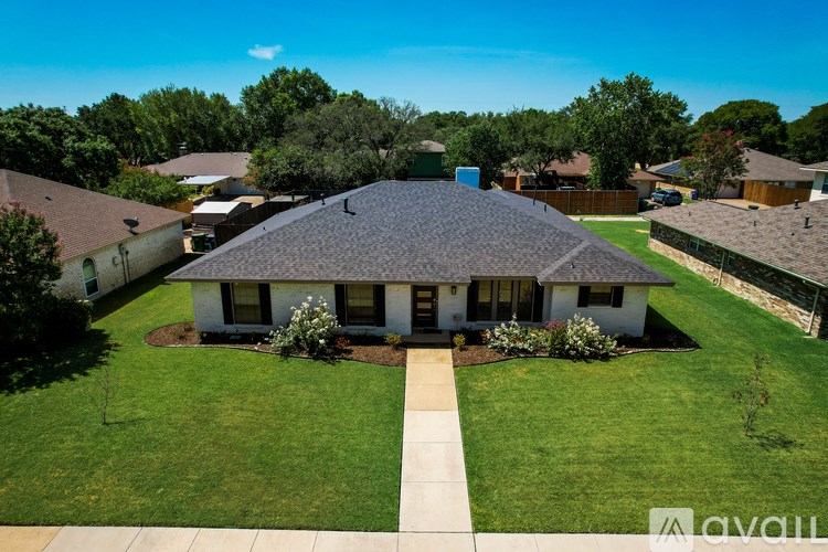 A house with a well-manicured lawn and a clear blue sky above.