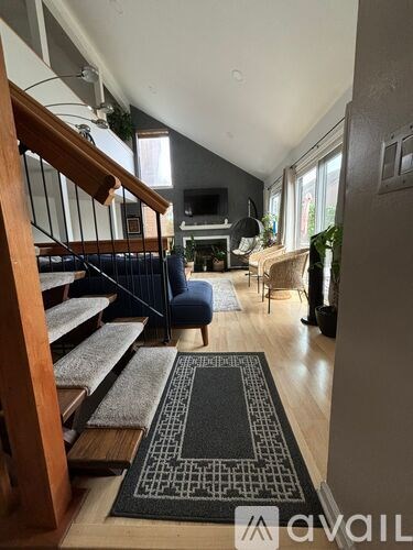A living room with a staircase and a rug in the foreground.