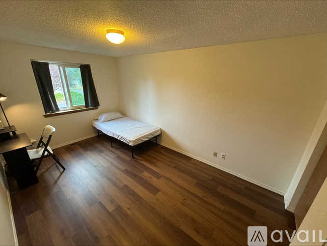 A room with a bed, desk, and chair.