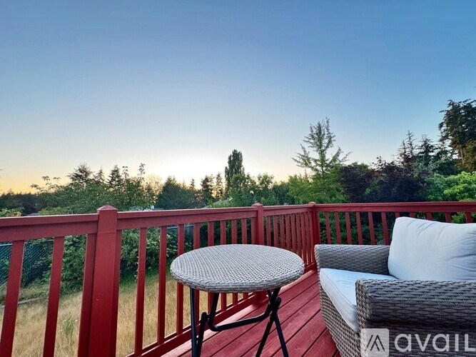 A red deck with a table and couch overlooking a forest.