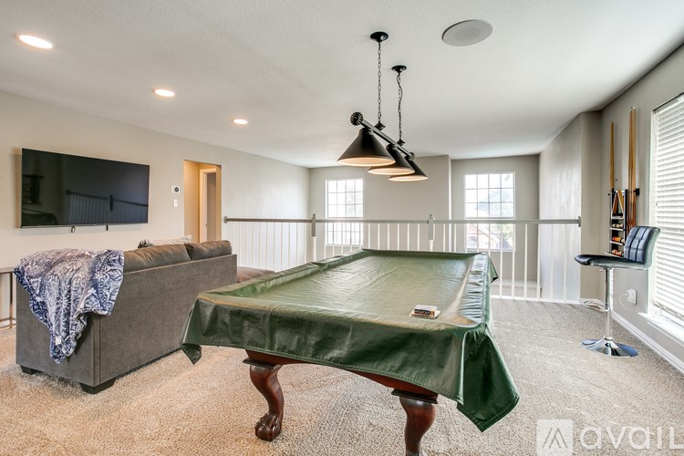 A living room with a grey couch and a green tablecloth on the table.