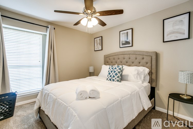 A bedroom with a large bed, a ceiling fan, and a window with blinds.