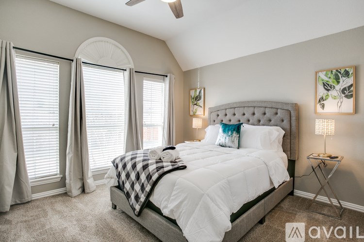 A bedroom with a large bed and a ceiling fan.