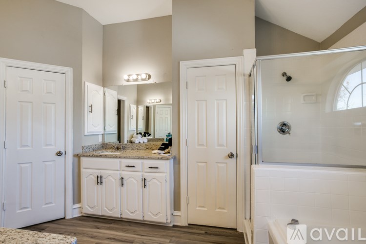 A bathroom with a vanity, mirror, and a bathtub.