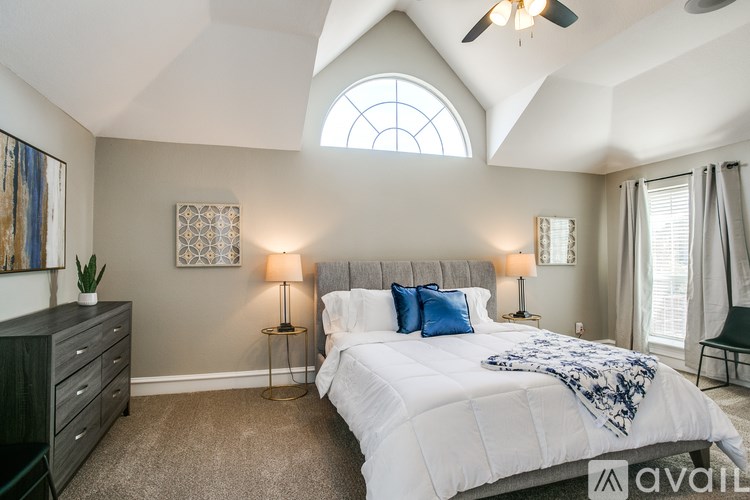 A bedroom with a large bed and a ceiling fan.