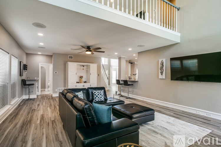 A living room with a black couch and a ceiling fan.