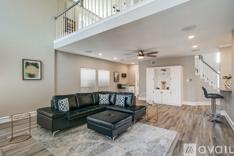 A living room with a black couch and a grey rug.