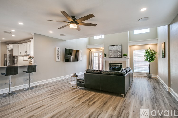 A spacious living room with a dark green couch and a ceiling fan.