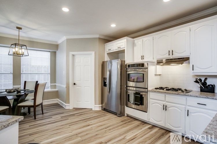 A kitchen with white cabinets and a wooden floor.