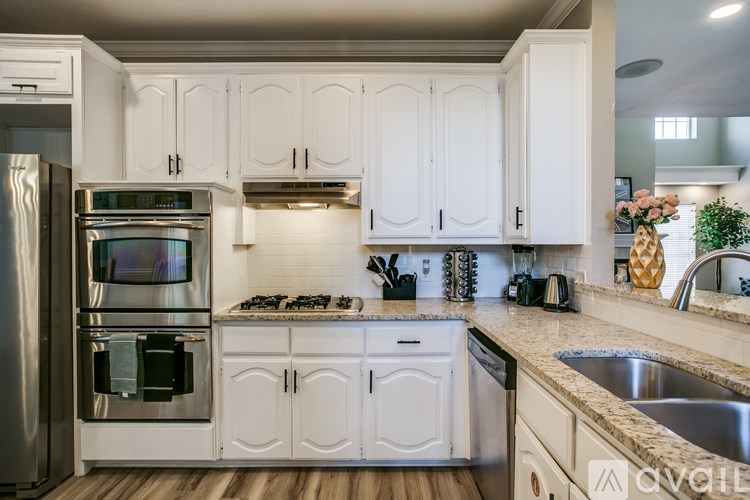 A kitchen with white cabinets and a stainless steel refrigerator.