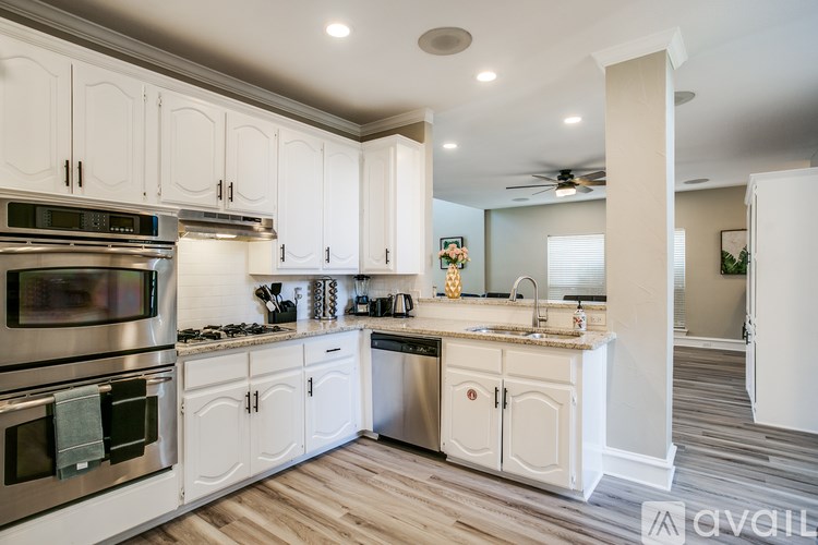 A modern kitchen with white cabinets and stainless steel appliances.