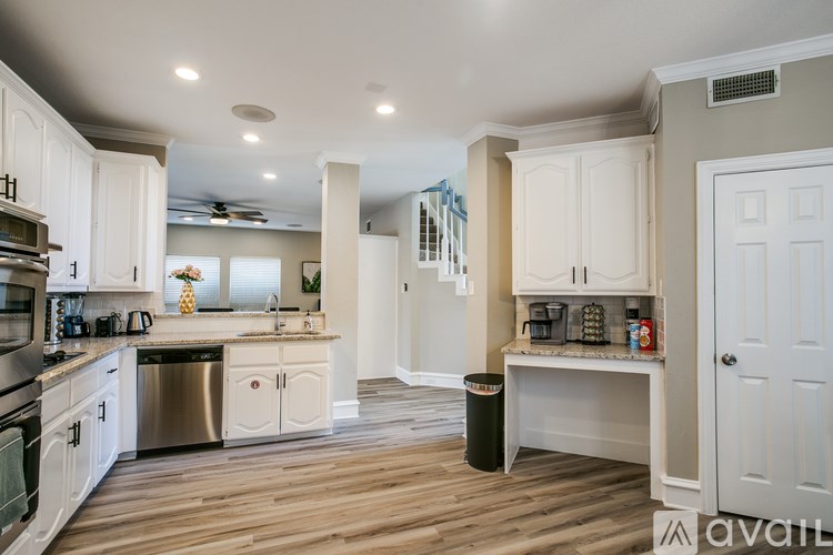A kitchen with white cabinets and a wooden floor.