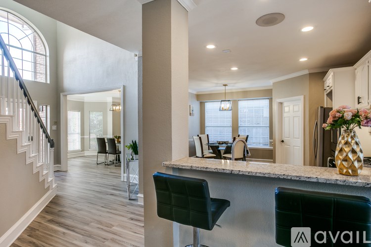 A modern kitchen with a bar area and a staircase.