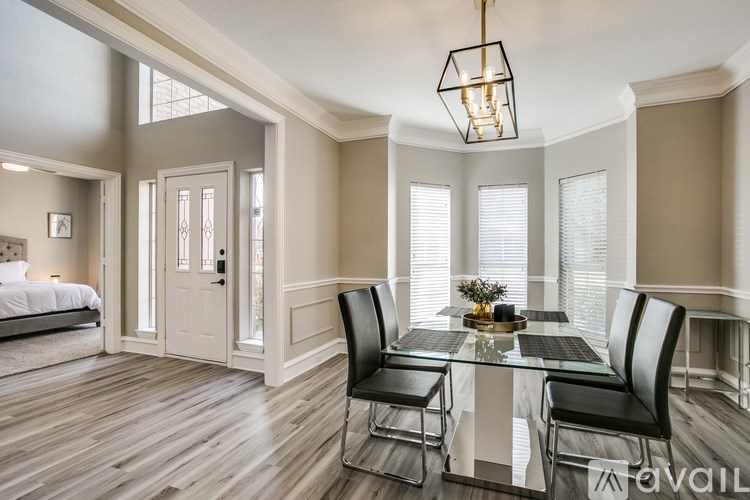 A modern dining room with a glass table and black chairs.