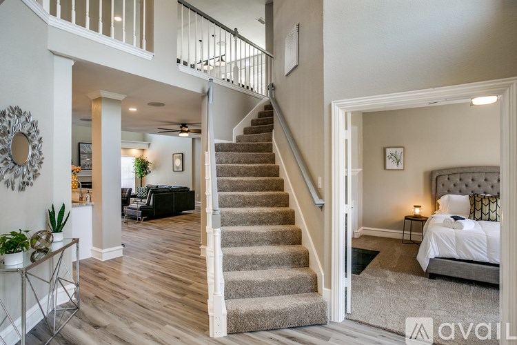 A bedroom with a large bed and a staircase leading to the upper floor.