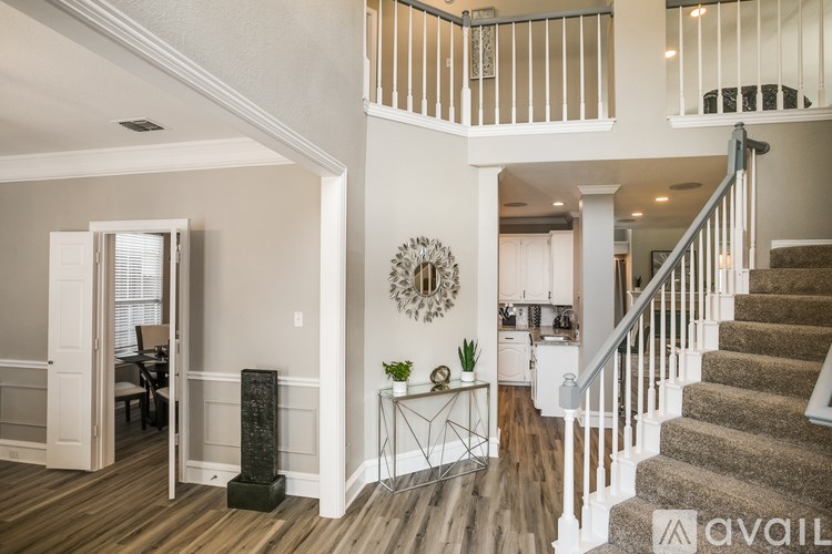 A large, well-lit living room with a staircase leading to the upper floor.