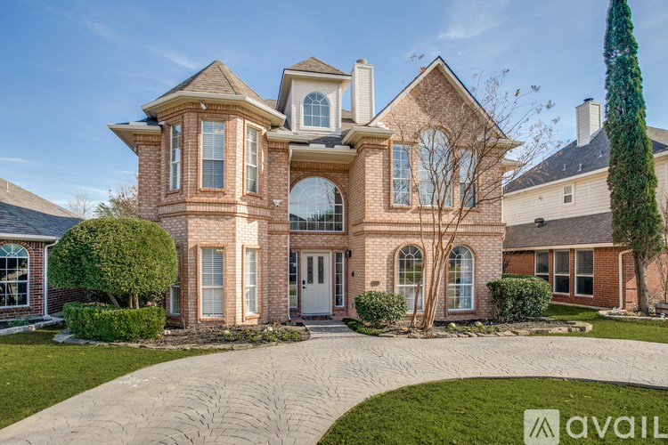A large, two-story house with a brick facade and a driveway in front.