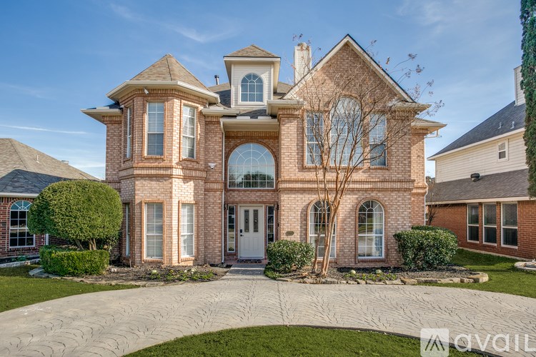 A large, two-story house with a brick facade and a large front yard.