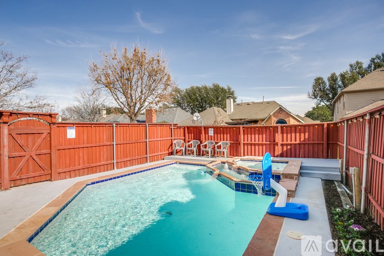 A pool surrounded by a red fence with a blue pool float in the middle.