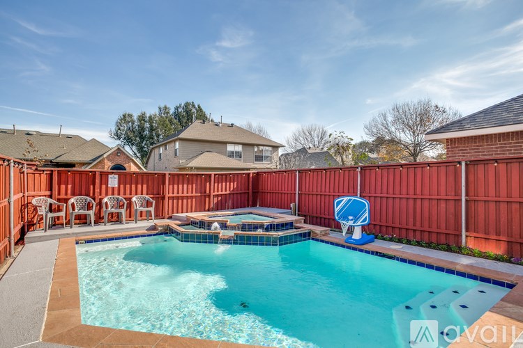 A pool surrounded by a red fence with a blue umbrella.