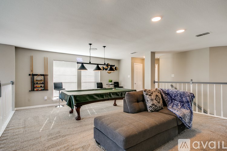 A living room with a couch, a table, and a pool table.