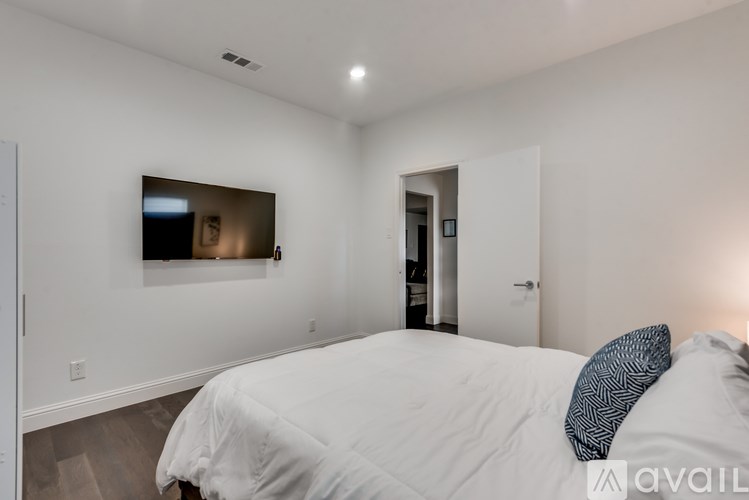 A bedroom with a large bed and a flat screen TV mounted on the wall.