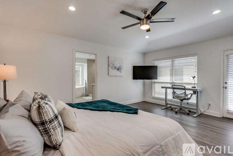 A bedroom with a bed, a chair, and a ceiling fan.