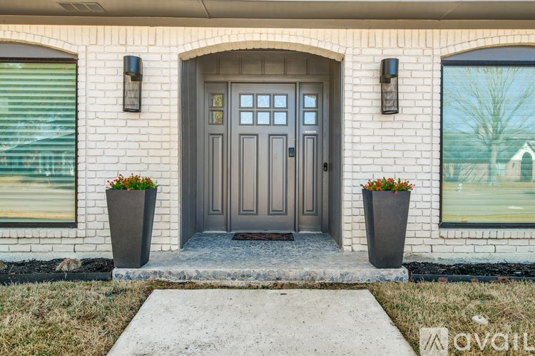 A house with a grey front door and two planters on either side.