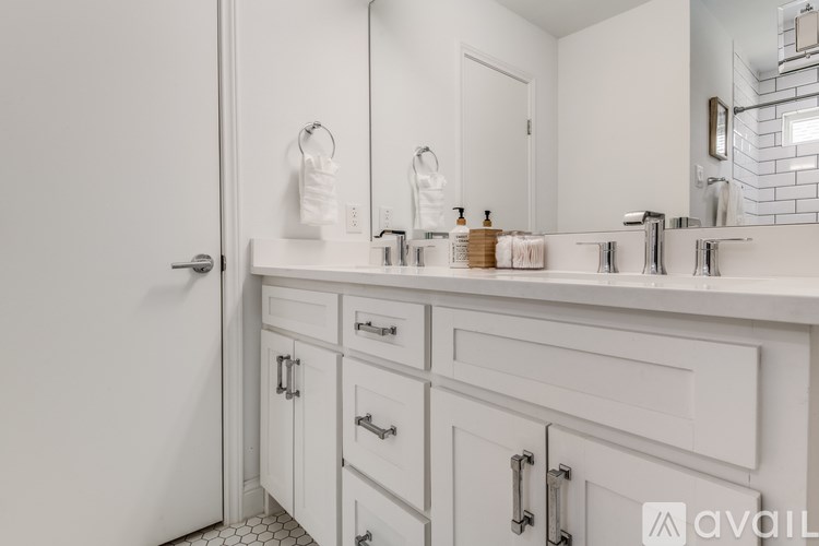 A bathroom with white cabinets and a white sink.