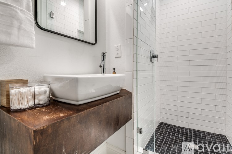 A bathroom with a copper sink and a glass shower door.