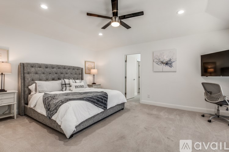A bedroom with a large bed and a ceiling fan.