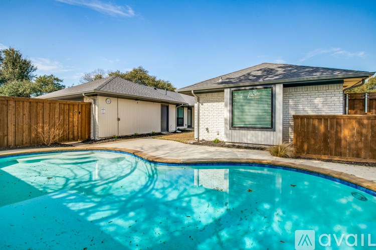 A pool in a backyard with a house and a fence.
