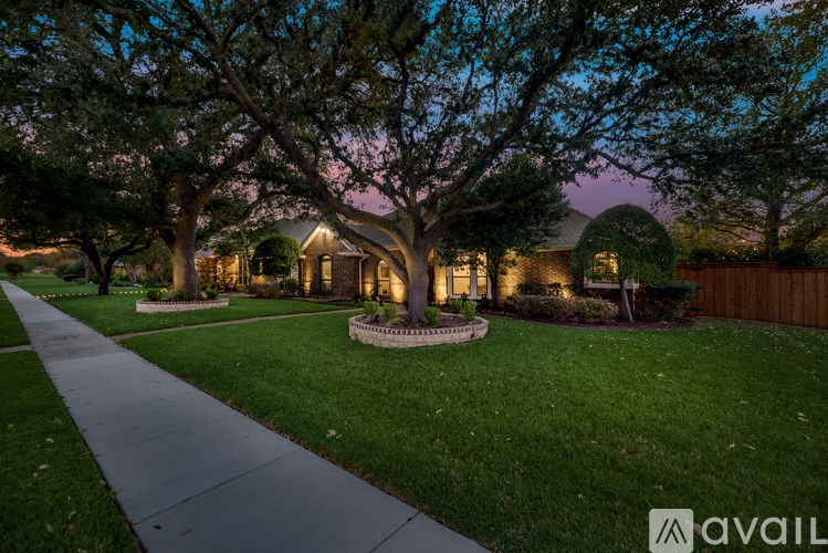 A house with a well-maintained lawn and trees in front of it.