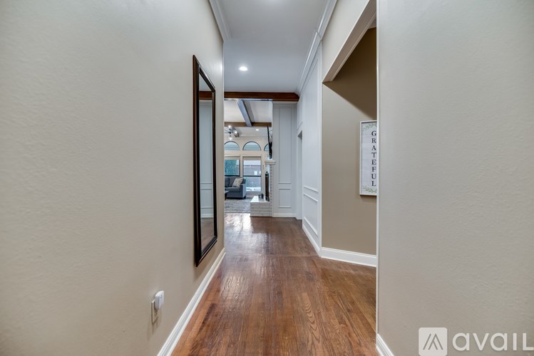 A hallway with wood floors and white walls.