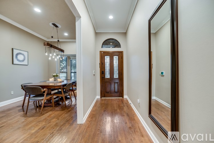 A hallway with a wooden floor and a dining table with chairs.