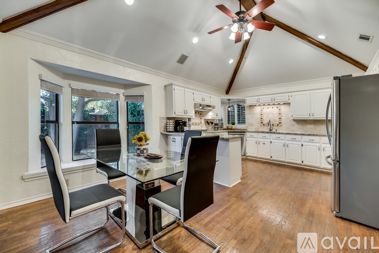 A kitchen with a table and chairs in the foreground and a refrigerator to the right.