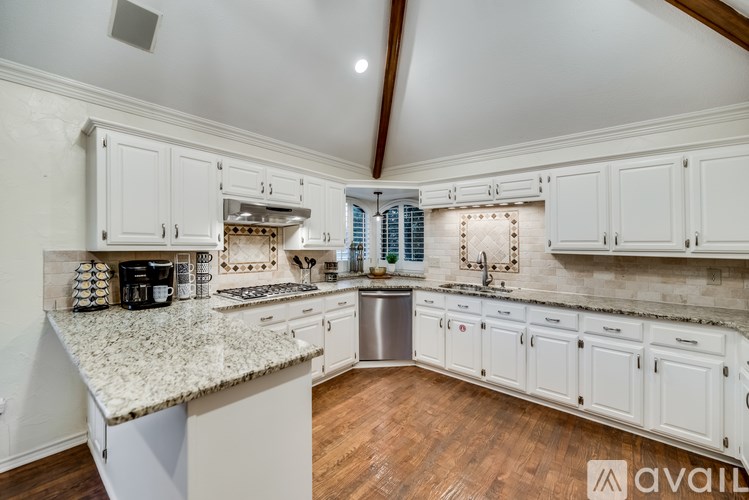 A kitchen with white cabinets and a granite countertop.