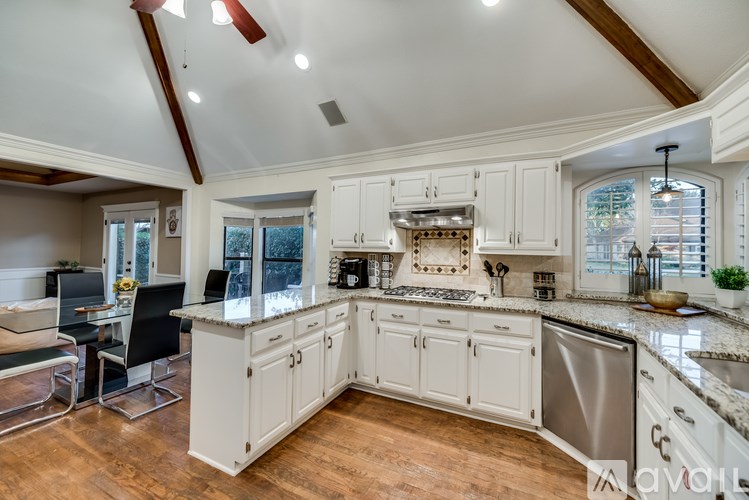 A modern kitchen with white cabinets and a wooden floor.