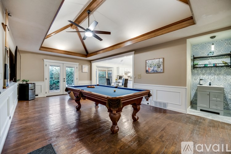 A pool table in a room with wooden floors and a ceiling fan.