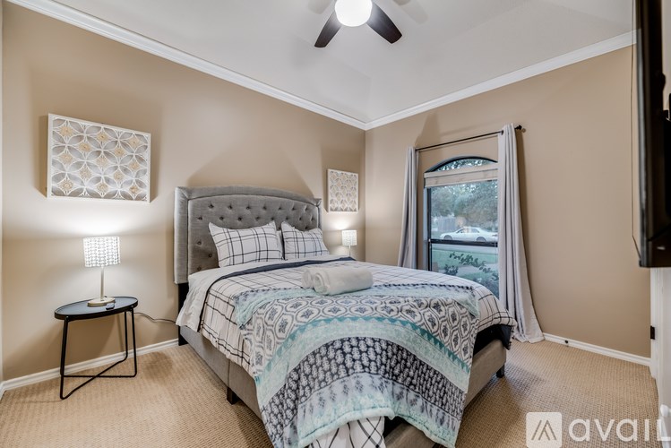 A bedroom with a bed, a ceiling fan, and a window with a view of a tree.