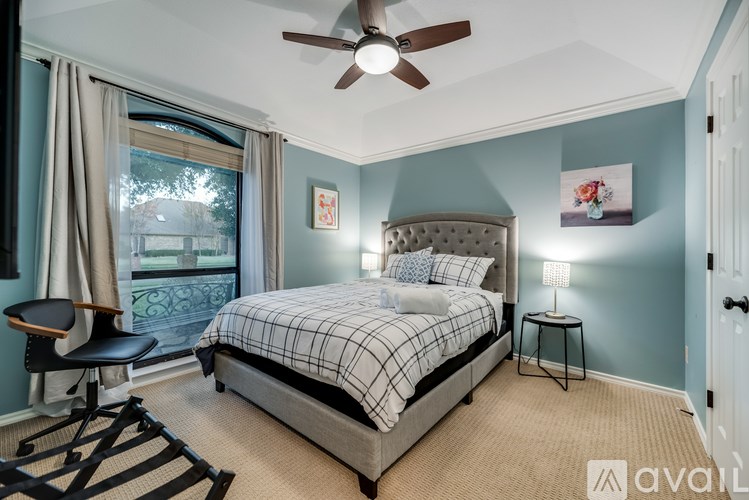 A bedroom with a bed, chair, and window.