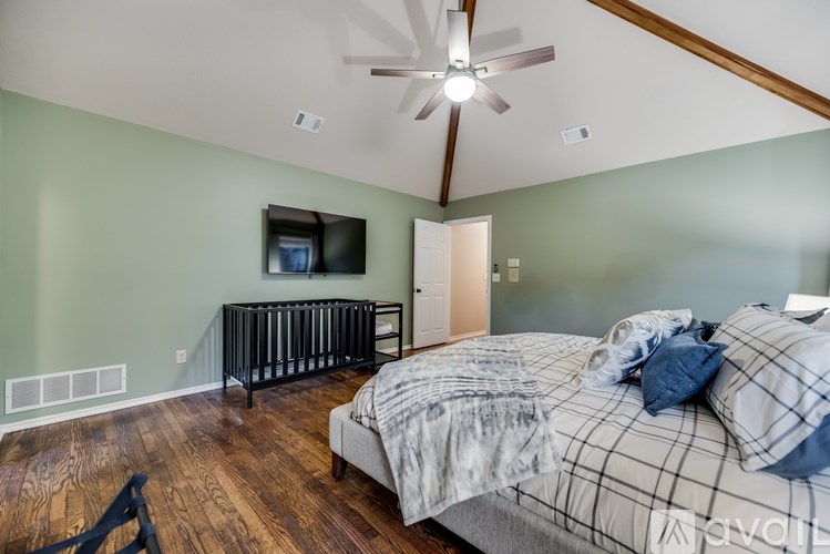 A bedroom with a bed, a television, and a baby crib.
