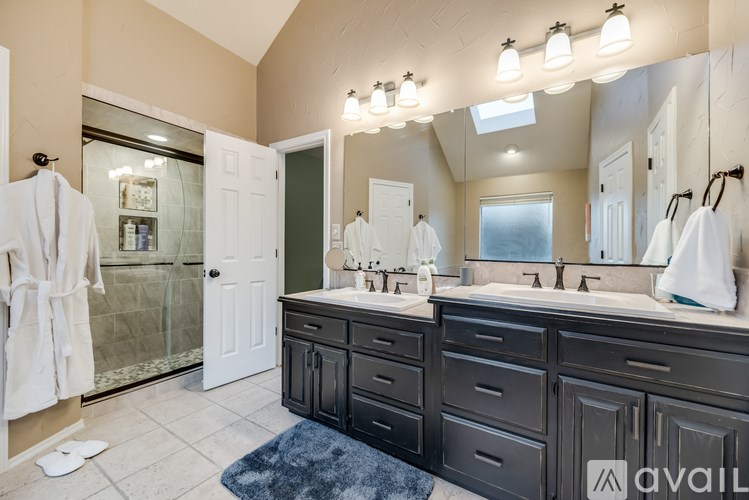 A bathroom with a large mirror, two sinks, and a glass shower door.
