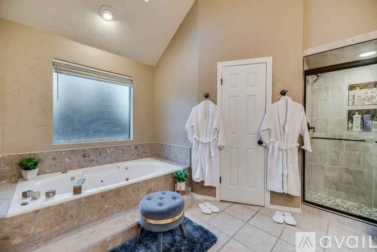 A bathroom with a tub, towels, and a window.
