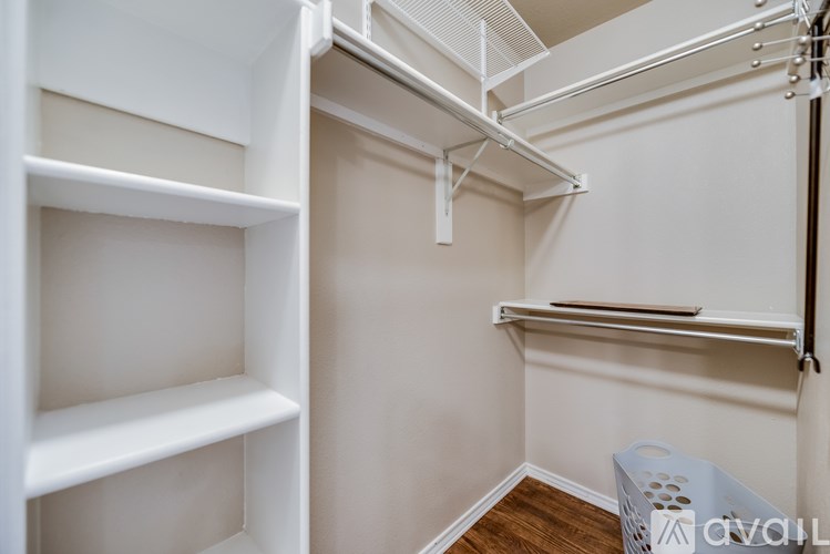 A white closet with shelves and a basket on the floor.