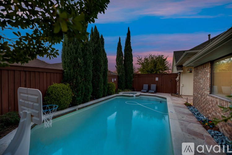 A pool surrounded by trees and a house with a chair and a net.
