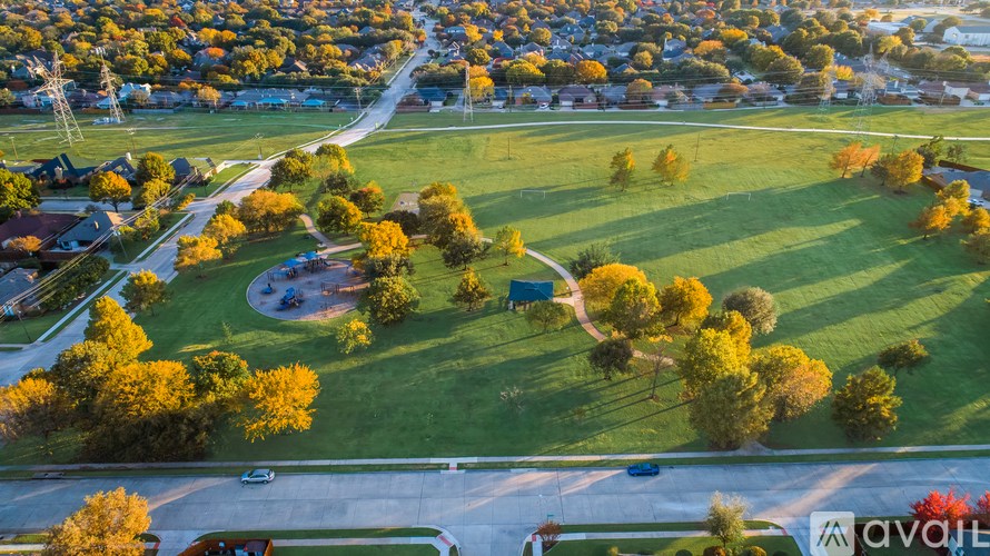 A park with a sign that says "available" is surrounded by houses.