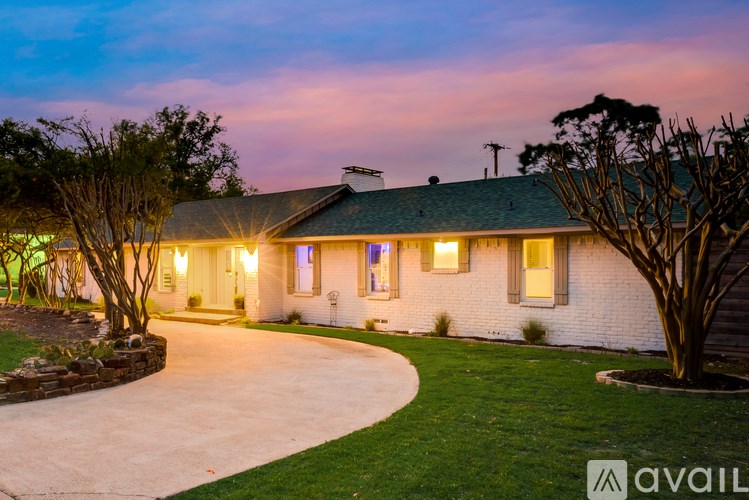 A house with a driveway and trees in front of it.