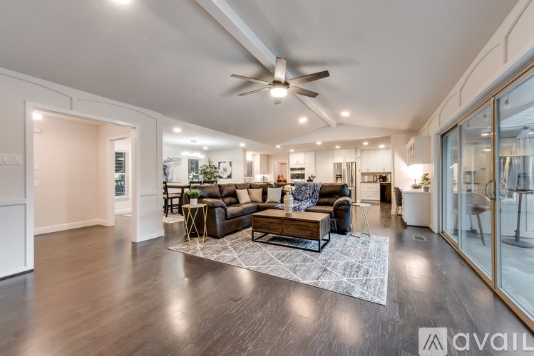 A spacious living room with a dark wood floor and a ceiling fan.