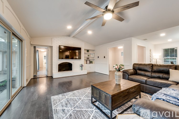 A living room with a fireplace and a ceiling fan.
